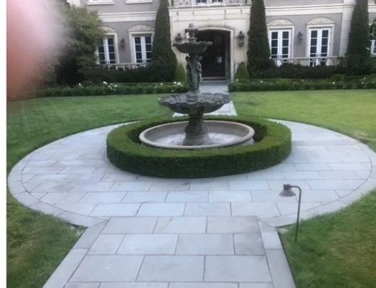 Circular paved garden court centered on a fountain and clipped hedge
