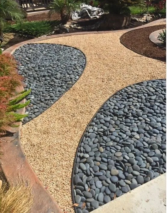Curved river-stone insets separated by tan gravel and black landscape edging