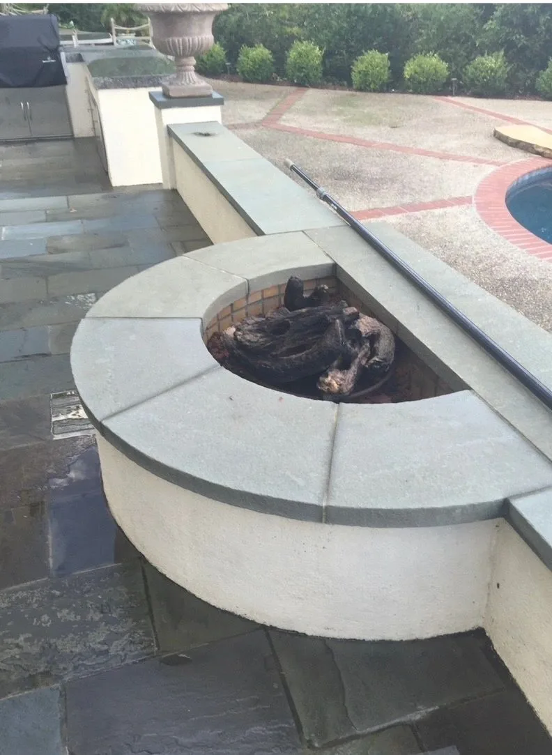Curved stone firepit beside a paved pool deck