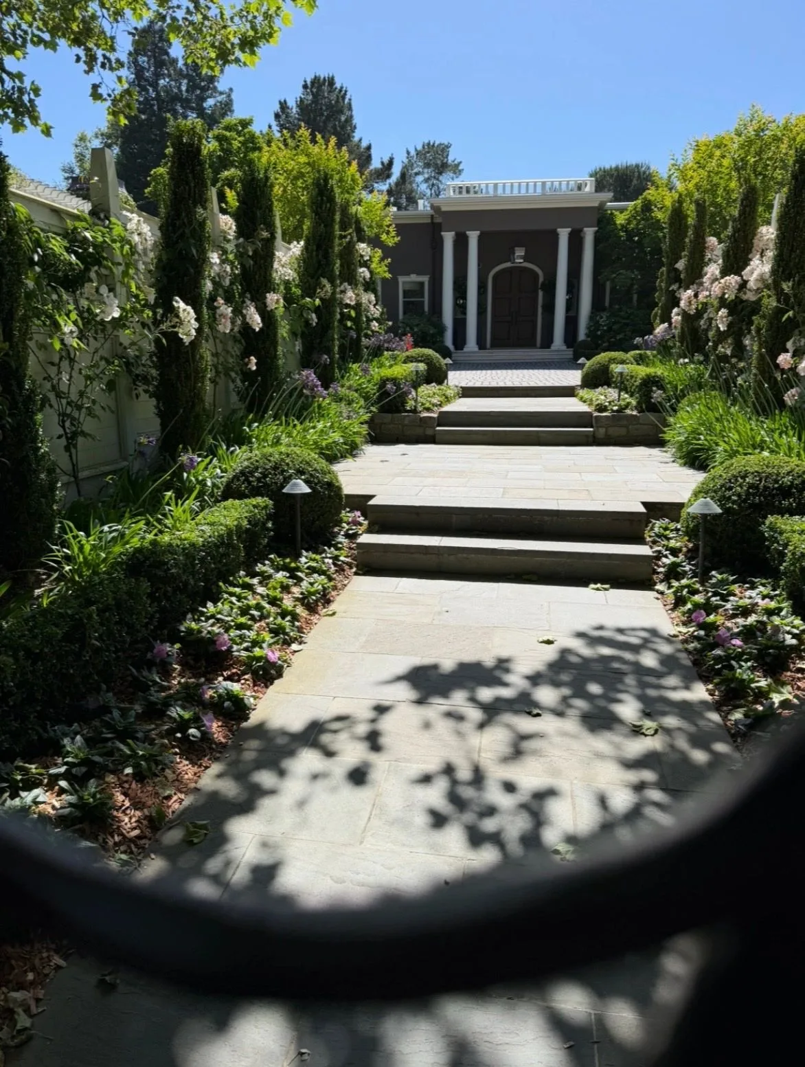 Elegant garden pathway leading to a grand house entrance with columns