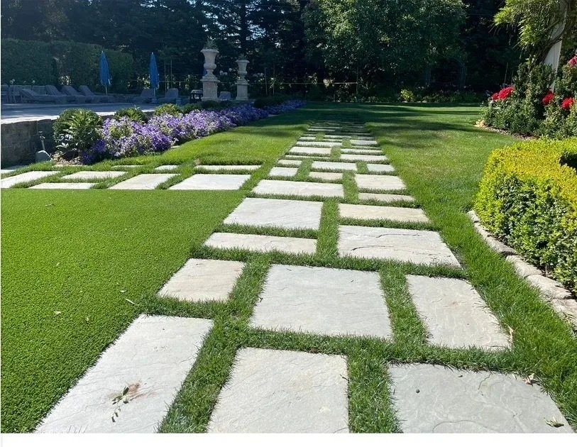 Large square stone pavers set into a precisely maintained lawn