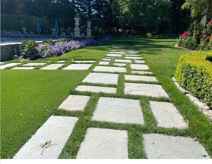 Large square stone pavers set into a precisely maintained lawn