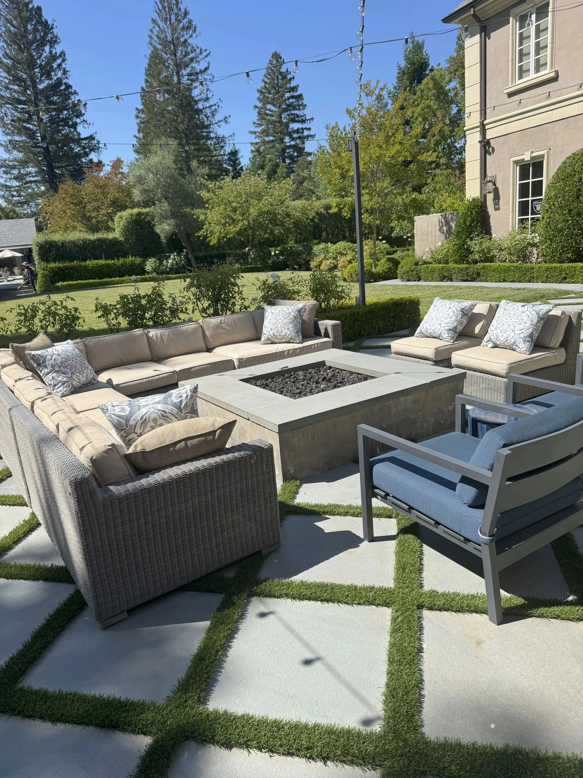 Outdoor lounge seating arranged on square pavers divided by narrow lawn strips