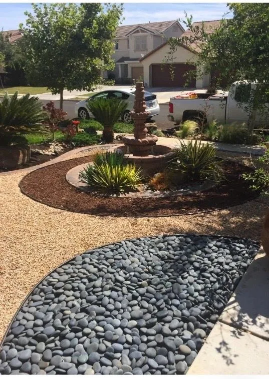 Curved inset of smooth dark river stones within a pale gravel path